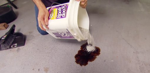 Pouring kitty litter on oil on a concrete garage floor.