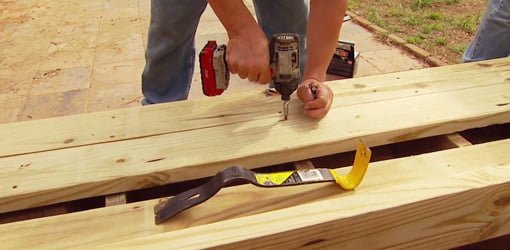 Using a cordless drill and deck screws to attach new wood decking.
