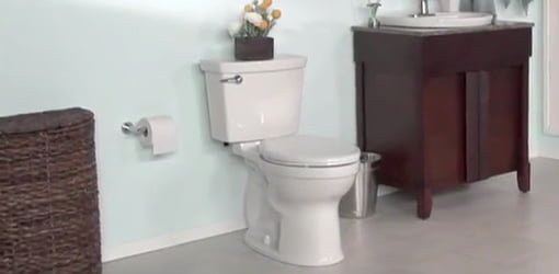 White toilet in bathroom with blue walls and stained wood furniture style vanity.