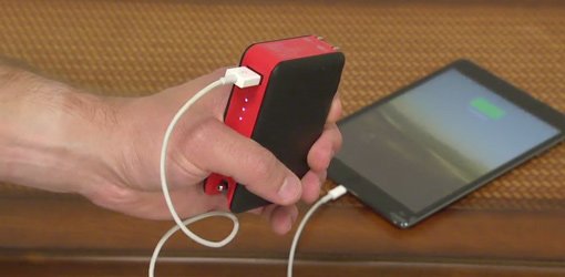 Hand holding Transit myCharge portable battery recharger plugged into smartphone.