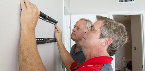 Allen Lyle and Danny Lipford hang a wall-mounted TV.
