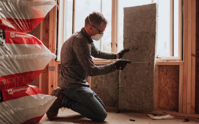 Man cutting stone wool insulation for interior wall installation