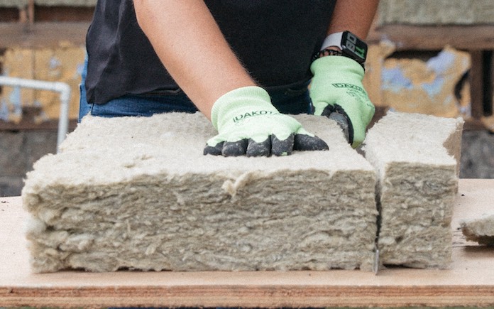 Gloved hands cutting stone wool insulation