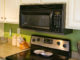 An over-the-range microwave oven in kitchen with green walls and laminate countertops