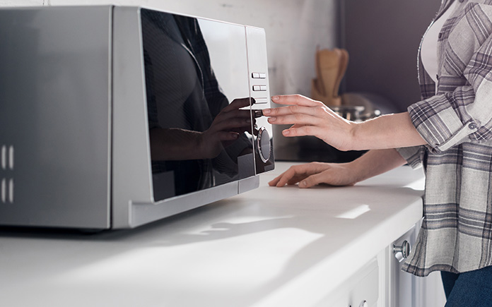 Woman's hand touches a microwave in a college dorm in North Dakota