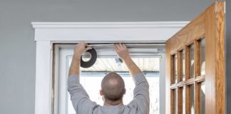 Man replaces weatherstripping in door frame