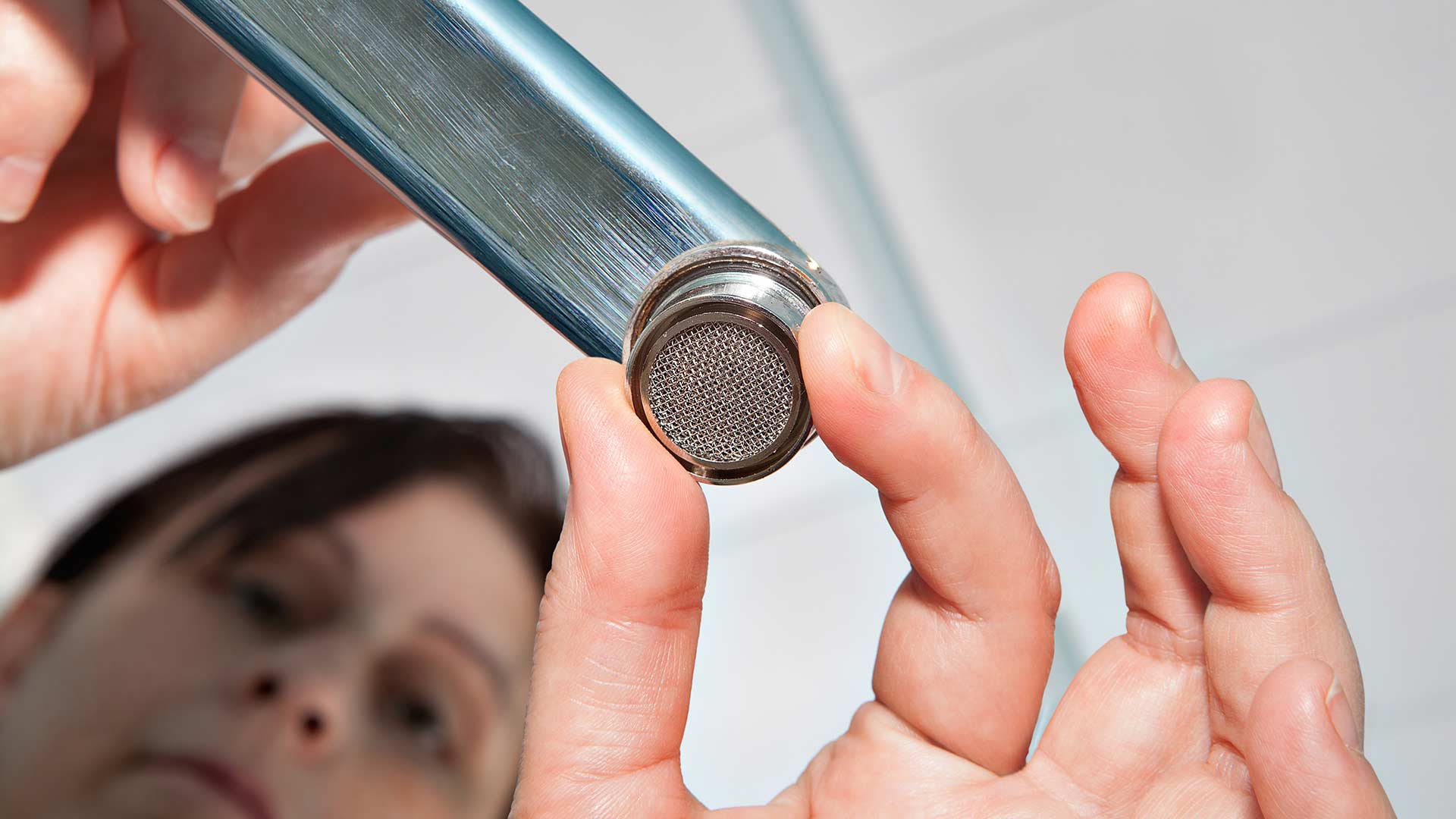 Woman unscrewing a faucet aerator.