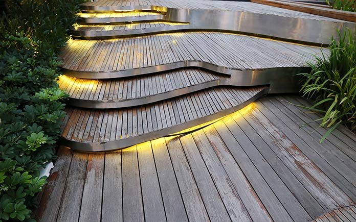 Lighted path in front of a home on wood deck stairs