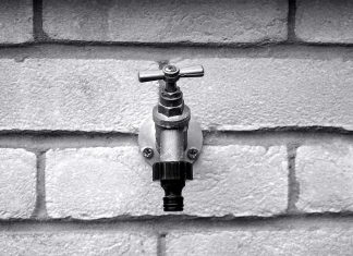 Outdoor faucet, seen close up, in grayscale.