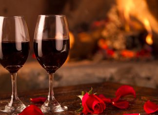 Wine glasses and rose petals, set on a table, in front of a roaring fire, on Valentine's Day