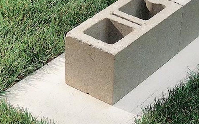 Setting the bottom cinderblock of a concrete wall