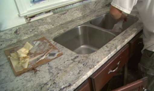 Stainless steel undermount sink being attached to granite countertops.