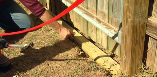 Installing wood to prevent dogs from digging under a gate