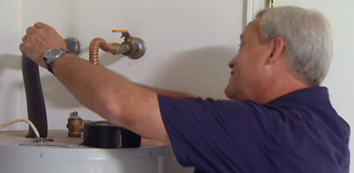 Danny Lipford insulating the pipes on a hot water heater.