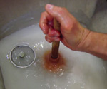 Using a plunger to unclog a kitchen sink drain.