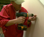 Using drill to drive screw into drywall.