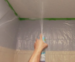 Applying textured ceiling spray to textured ceiling.