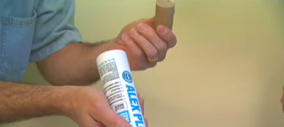 Take the caulking tube out of the gun and insert the dowel in the tube.