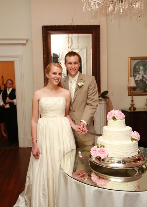 Bride and groom cutting white wedding cake