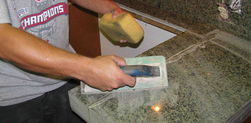 Using a rubber float and sponge to apply grout to tile.