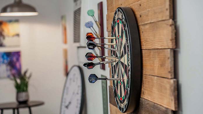Dartboard in the garage; installed on a wooden pallet accent wall