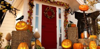 Front porch of a home during the morning, with jack-o-lanterns on the floor and fall decorations adorning the wood trim