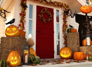 Front porch of a home during the morning, with jack-o-lanterns on the floor and fall decorations adorning the wood trim