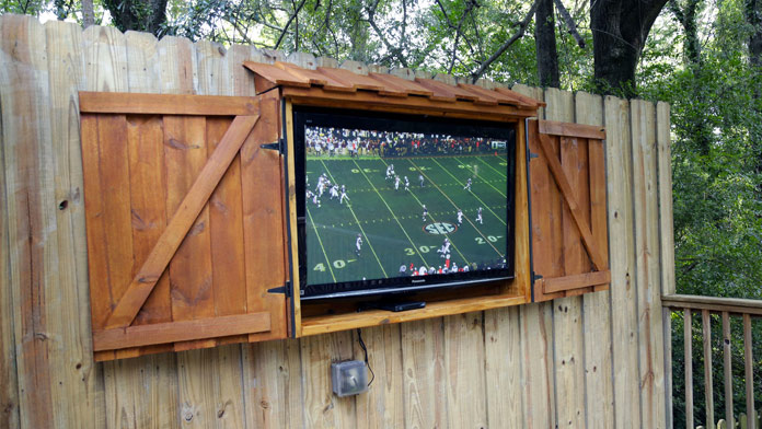 Football game playing on a flat screen TV housed in an outdoor TV cabinet made of wood