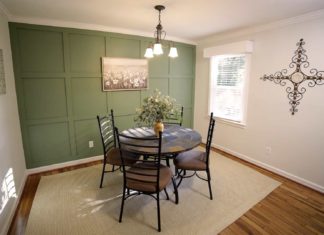 Dining room with green accent wall and chandelier above the table
