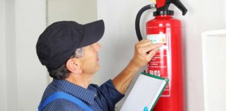Man services a fire extinguisher that's hanging on the wall