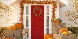 Exterior Thanksgiving décor featuring fall garland, pumpkins, bales of hay and pumpkins