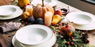 Thanksgiving table set with chargers, dinner plates and pumpkins