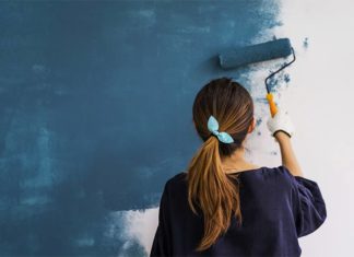 Young woman painting a blue wall