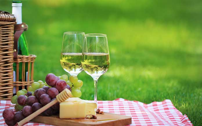 Wine and cheese tray arranged on a picnic tablecloth