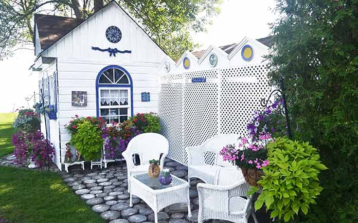 White storage shed that matches the white nearby patio and privacy fence