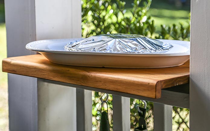 Wooden counter set on a porch railing with a platter on top
