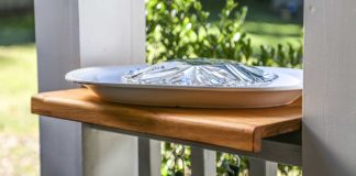 Wooden counter set on a porch railing with a platter on top