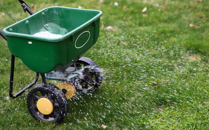 A seed and fertilizer spreader out on a lawn
