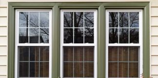 Three vinyl windows, seen close up, reflecting a picturesque neighborhood