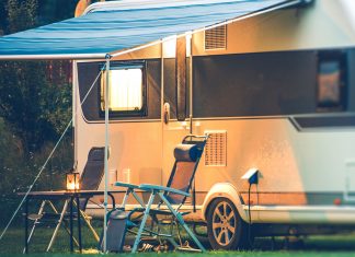Camper, as seen at night, with the two folding chairs under a pop-out awning