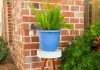 Plant stand made of three wood dowels and Quikrete concrete, outside, beside a brick home
