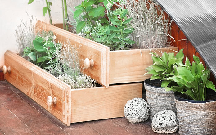 Old drawers used as planters in repurposed rustic garden outside townhome