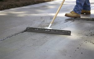 Man applies Quikrete Re-Cap Resurfacer to spalling concrete slab