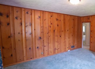Dated wood paneling in a bedroom with unsightly carpeting
