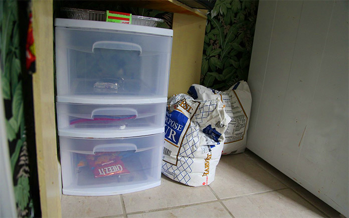 Plastic, two-tiered storage bins on the floor in a messy closet