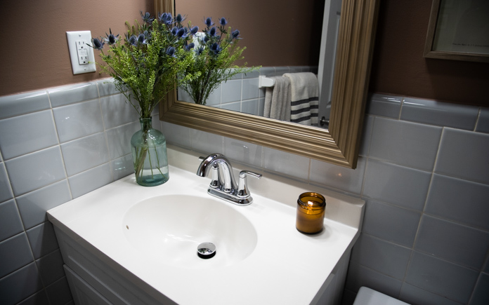 Remodeled bathroom with beautiful vanity, new mirror and candle and vase of flowers