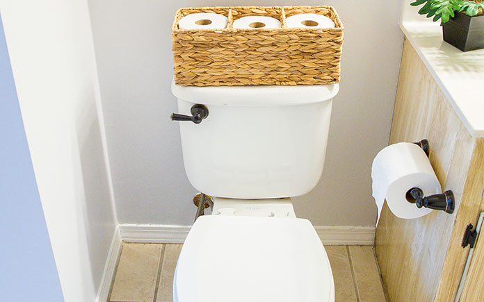 Toilet with basket of toilet paper on the tank