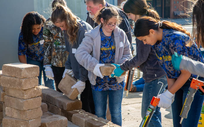 Students from Marianna Middle School work together to build the paver flower beds.