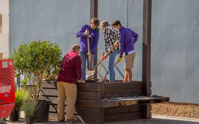 Students from Marianna High School work together to add plants to the large planters.