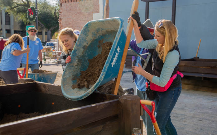 Local volunteer, Diane Pate, helps Chelsea fill the large planters with soil. 